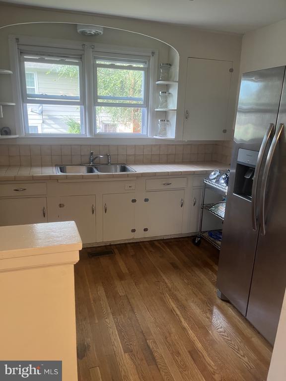 Kitchen with cream cabinets, a double window over the sink, wood flooring, and a stainless-steel refrigerator.