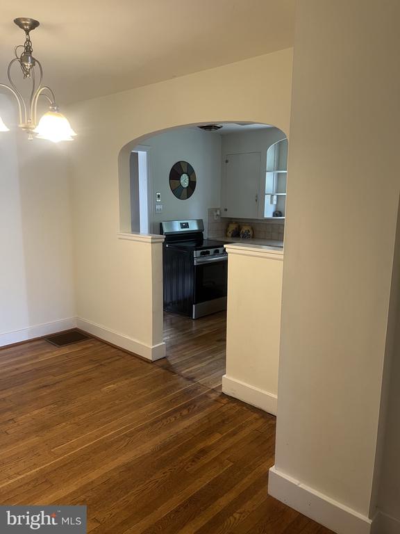 Empty dining area with hardwood floors and an arched opening into the kitchen.