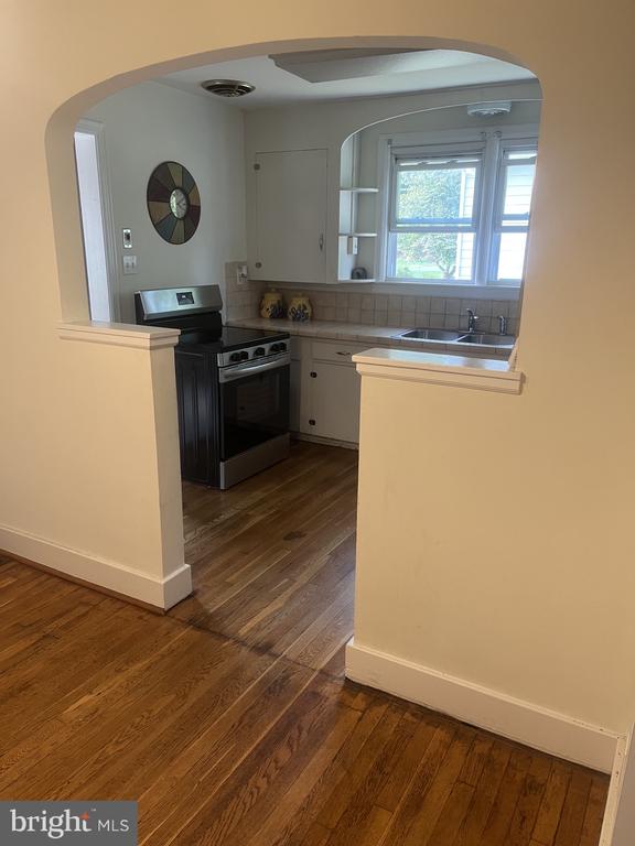 Kitchen with an arched pass-through, hardwood floors, and a stainless steel range.