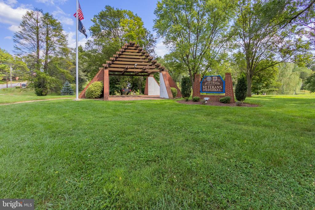 Jefferson County Veterans Memorial beneath a timber pergola, with flags and mature trees.