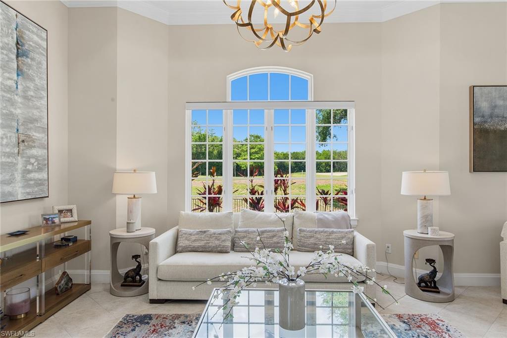 Staged living room with a white sofa and a large arched window overlooking the lawn.
