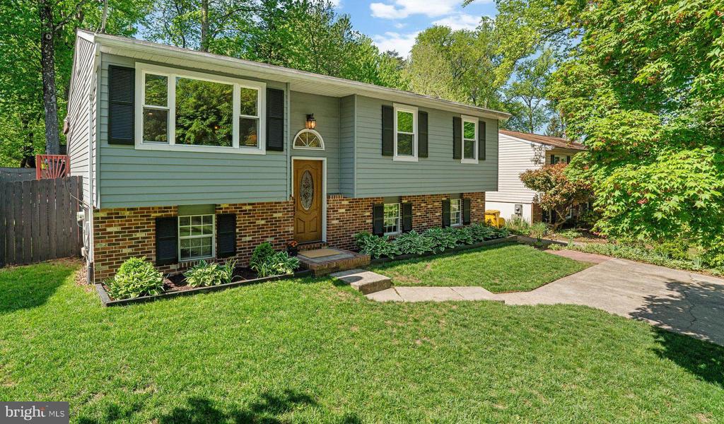 Split-level house with gray siding, brick lower level, and a broad green lawn.