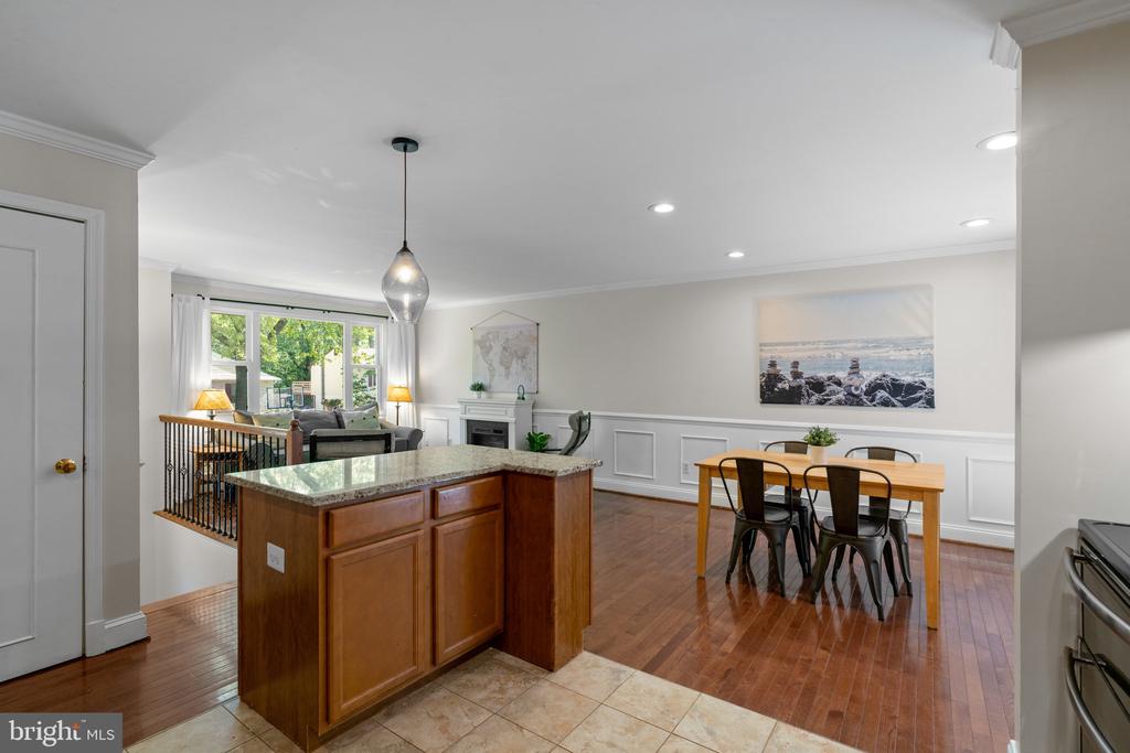 Open-plan kitchen and dining area with a granite-topped wood island and hardwood floors.
