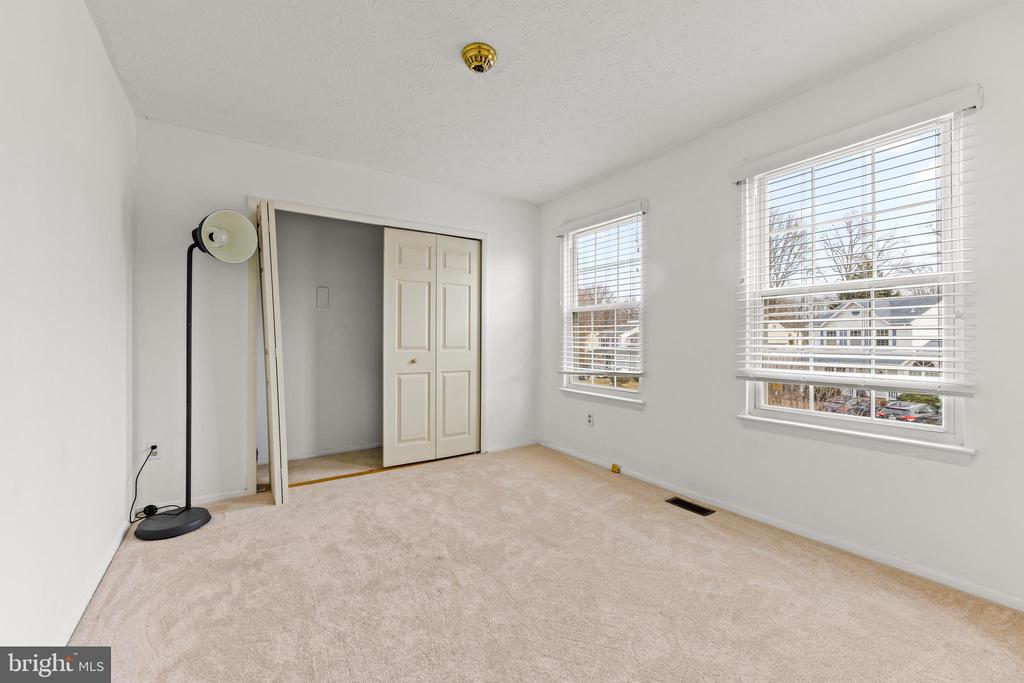 Empty carpeted bedroom with two windows and a sliding-door closet.