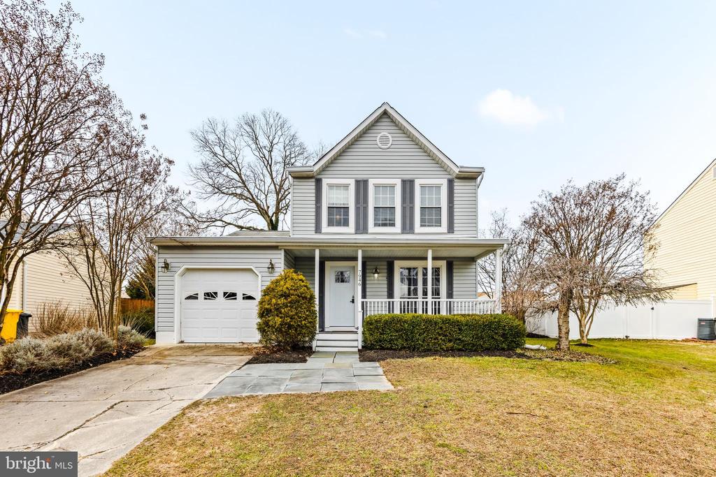 Gray two-story house with a covered porch, attached garage, and leafless trees.