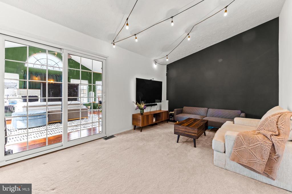 Living room with a charcoal accent wall, sofas, wood coffee table, and glass doors to a sunlit adjoining room.