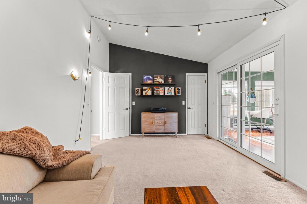 Living room with a charcoal accent wall, record shelves, and sliding glass doors to a sunroom.