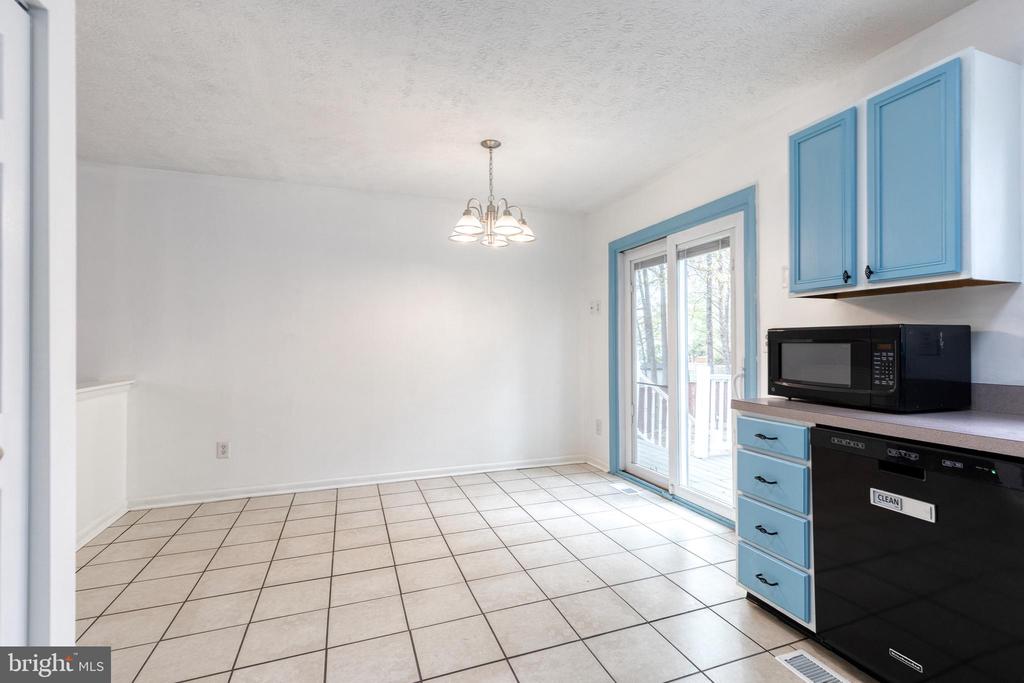 Empty dining area with tiled floor, blue kitchen cabinets, and sliding glass doors.