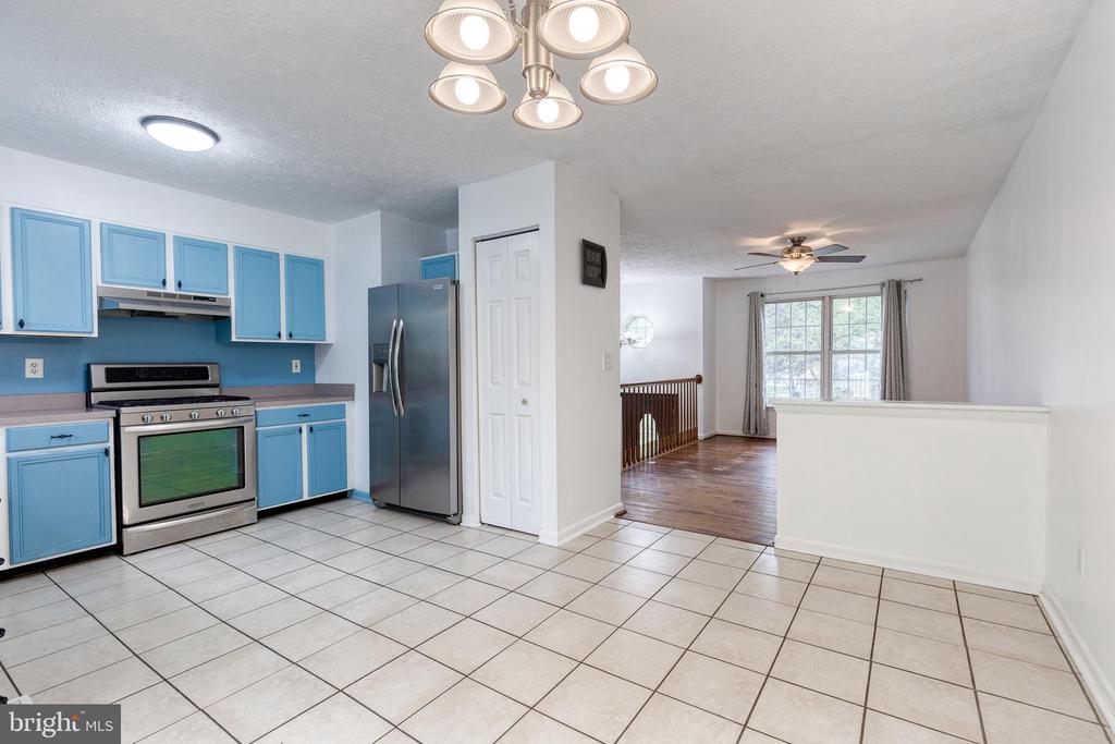 Kitchen with bright blue cabinets, stainless steel appliances, and an adjoining dining area with a large window.
