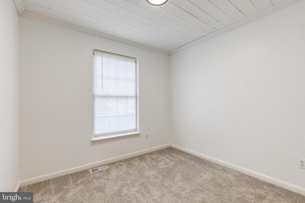 Empty bedroom with beige carpet, white walls, and a window with closed blinds.