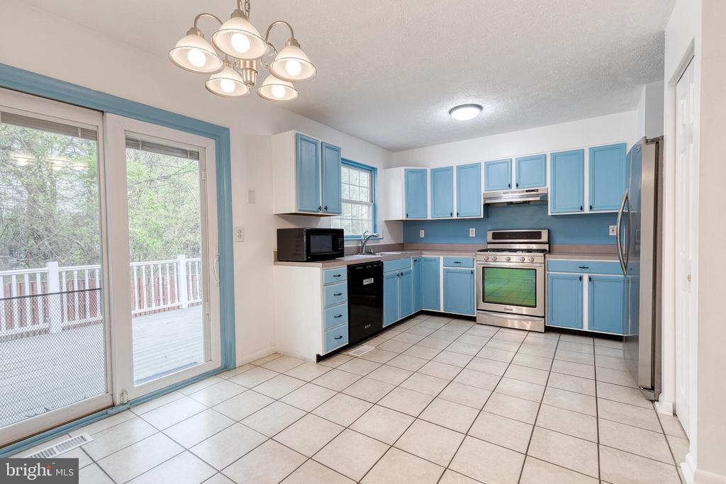 Kitchen with blue cabinets, stainless steel appliances, and a sliding glass door to the deck.