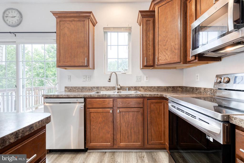 Kitchen with wood cabinets, granite countertops, stainless steel appliances, and a sliding glass door to a deck.