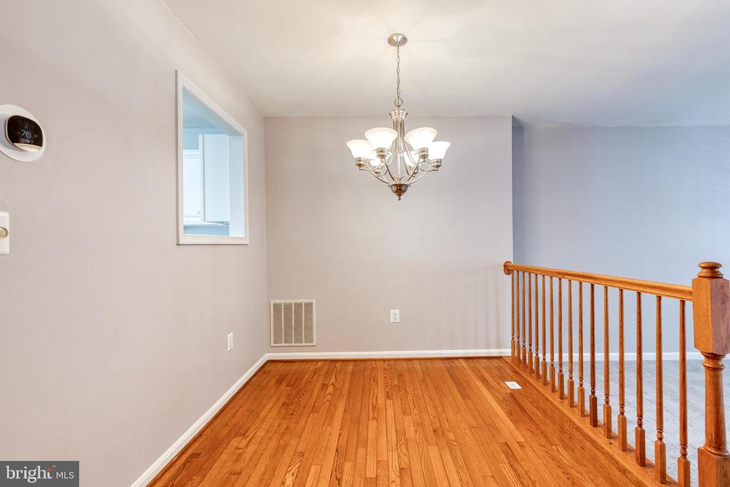 Empty room with polished hardwood floors, a chandelier, and a wooden railing.