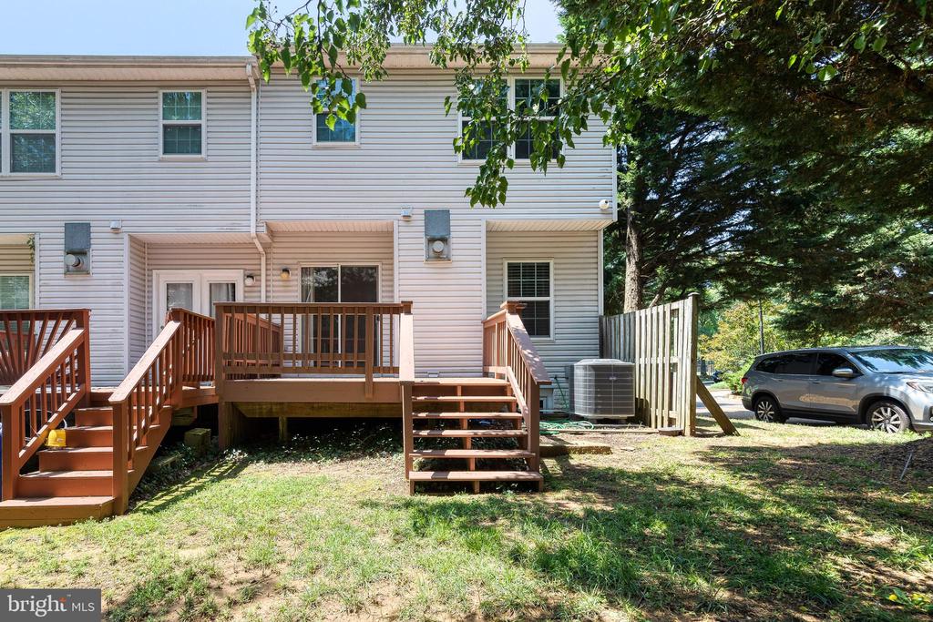 Rear exterior of a two-story home with raised wooden decks beneath mature trees.