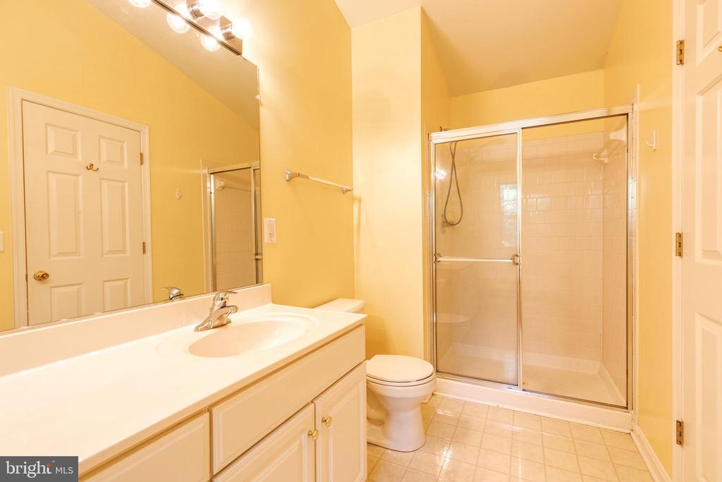 Bathroom with a long white vanity, toilet, and glass-enclosed tiled shower.