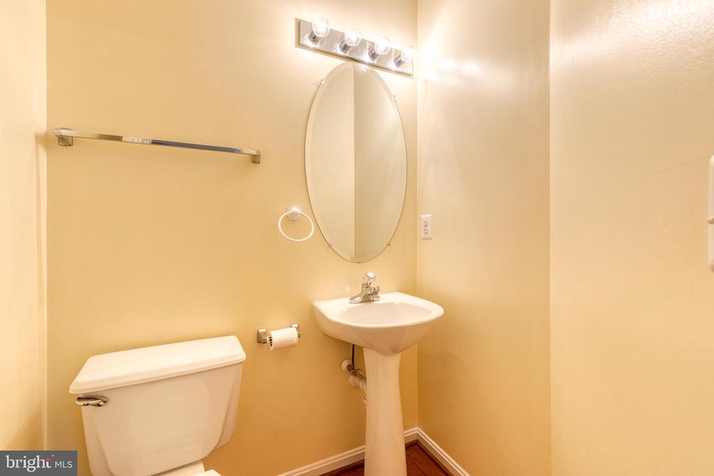 Small bathroom with a pedestal sink, oval mirror, and white toilet.
