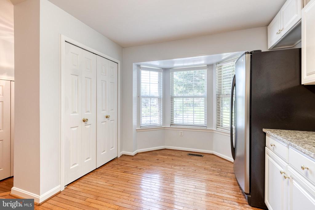 Kitchen with hardwood floors, white cabinetry, a dark refrigerator, and a bay window.