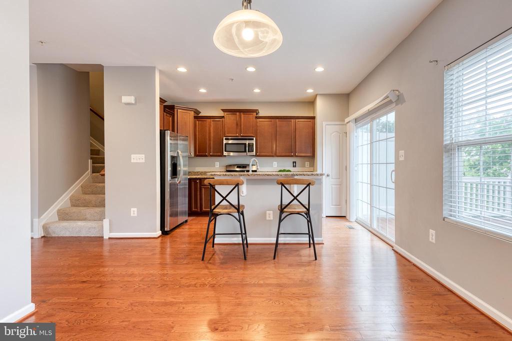 Kitchen with cherry cabinets, breakfast bar, stainless appliances, and adjoining hardwood-floored area.
