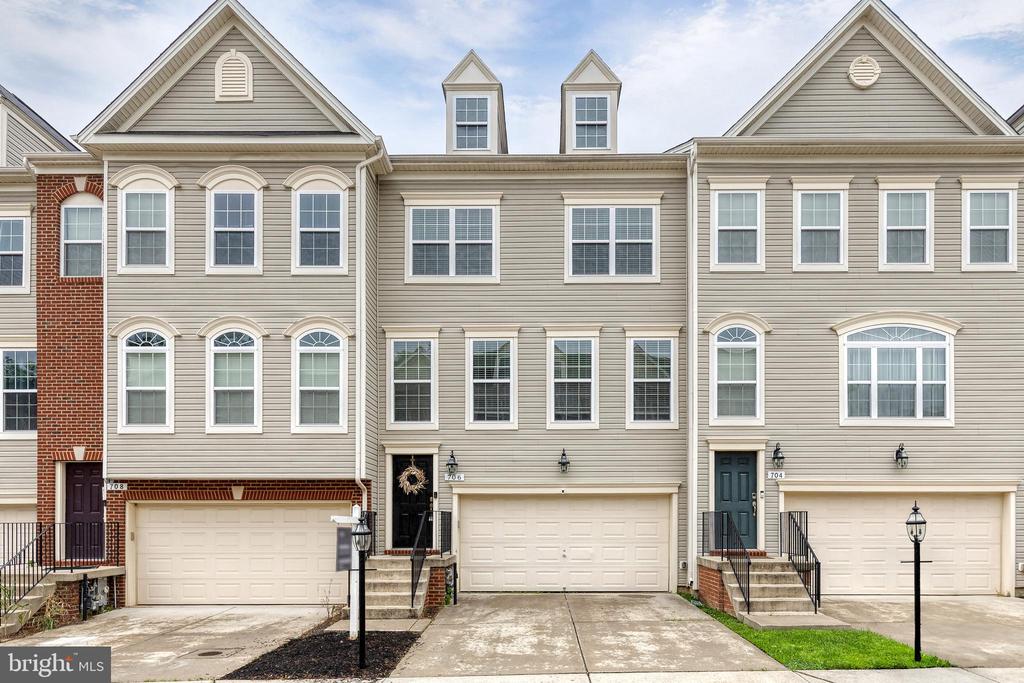 Beige townhouse with white-trimmed windows, a one-car garage, and front steps.