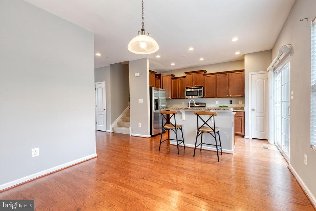Open kitchen with cherry cabinets, granite island, stainless steel appliances, and hardwood floors.