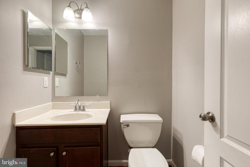 Bathroom with a dark wood vanity, white sink, toilet, and open door.