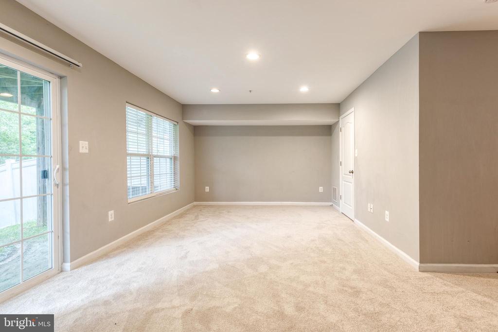 Empty carpeted room with recessed lights, a wide window, and a sliding glass door.