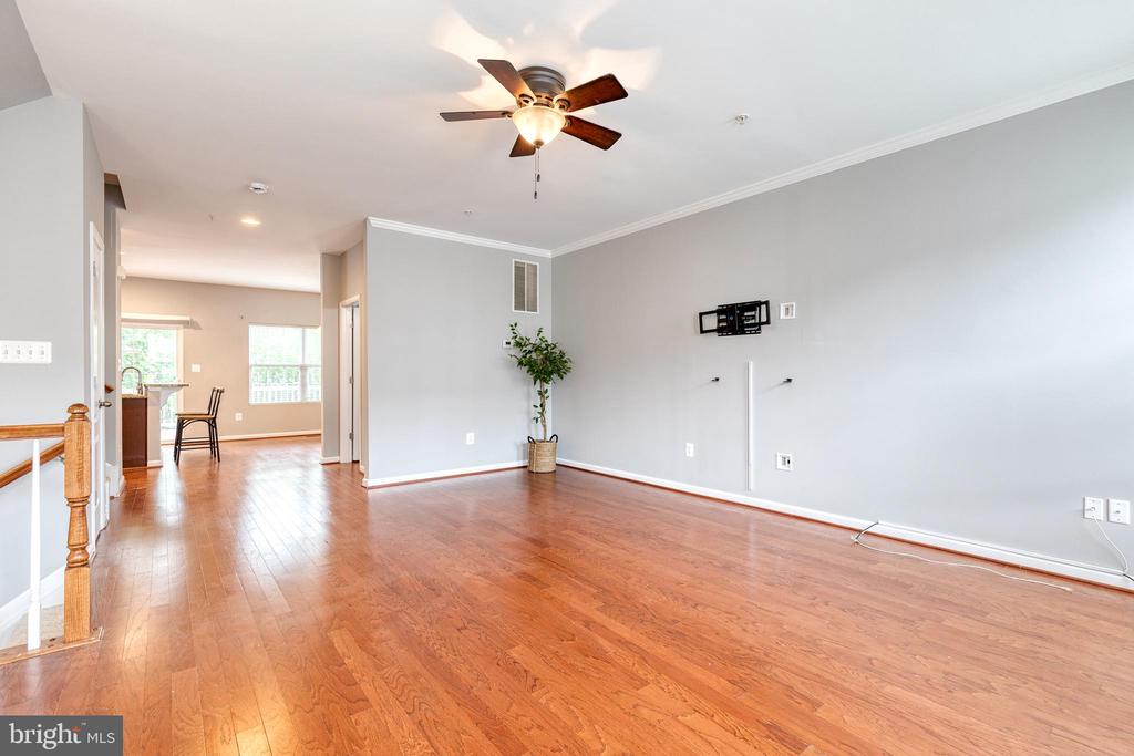 Living room with polished hardwood floors, gray walls, and a ceiling fan.