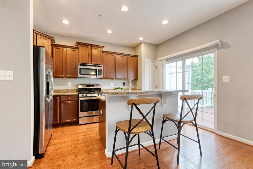 Kitchen with wood cabinets, stainless steel appliances, and a breakfast bar beside sliding glass doors.