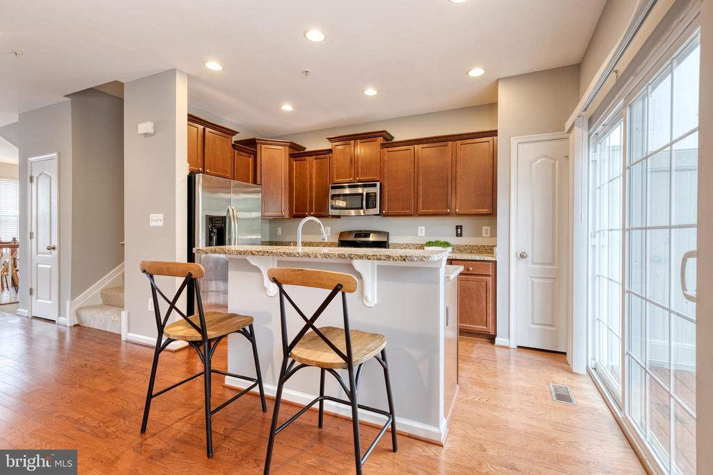 Kitchen with warm wood cabinets, stainless steel appliances, and an island beside large sliding glass doors.