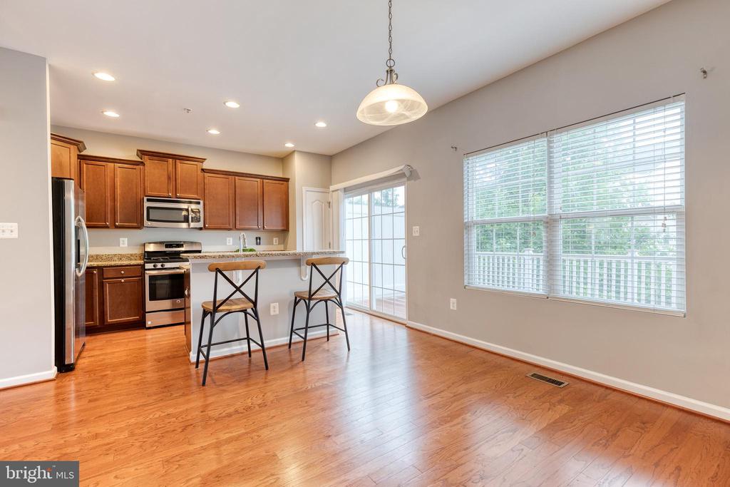 Kitchen and dining area with dark wood cabinets, stainless steel appliances, and hardwood floors.