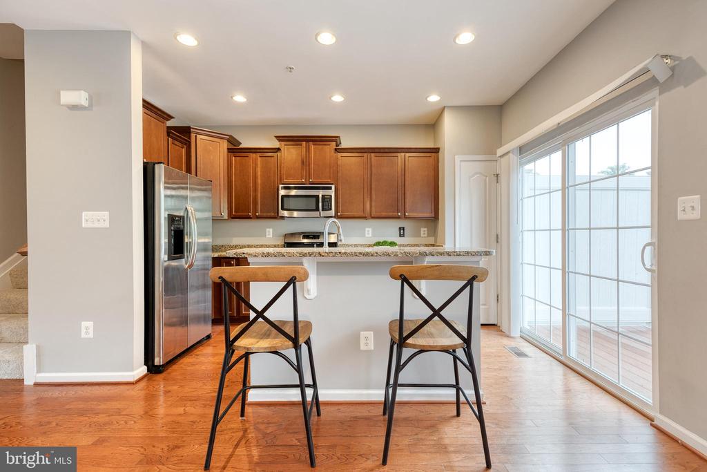 Kitchen with warm wood cabinets, granite breakfast bar, and sliding glass doors.