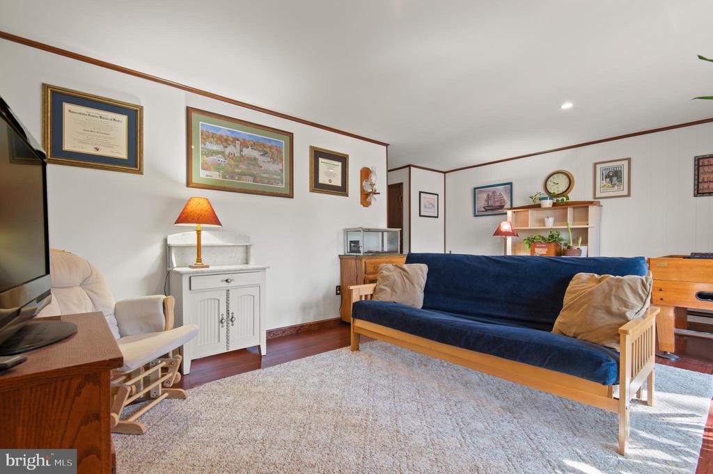 Living room with a navy sofa, beige cushions, framed artwork, and a large pale rug.