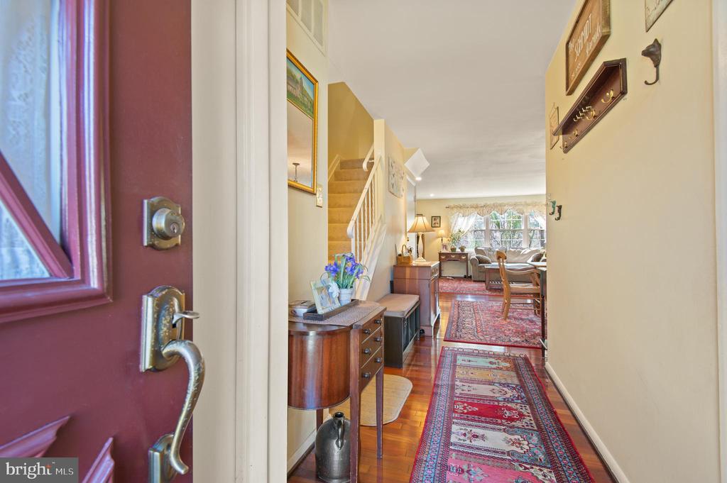 Furnished entry hall with a patterned runner leading toward a living room and staircase.