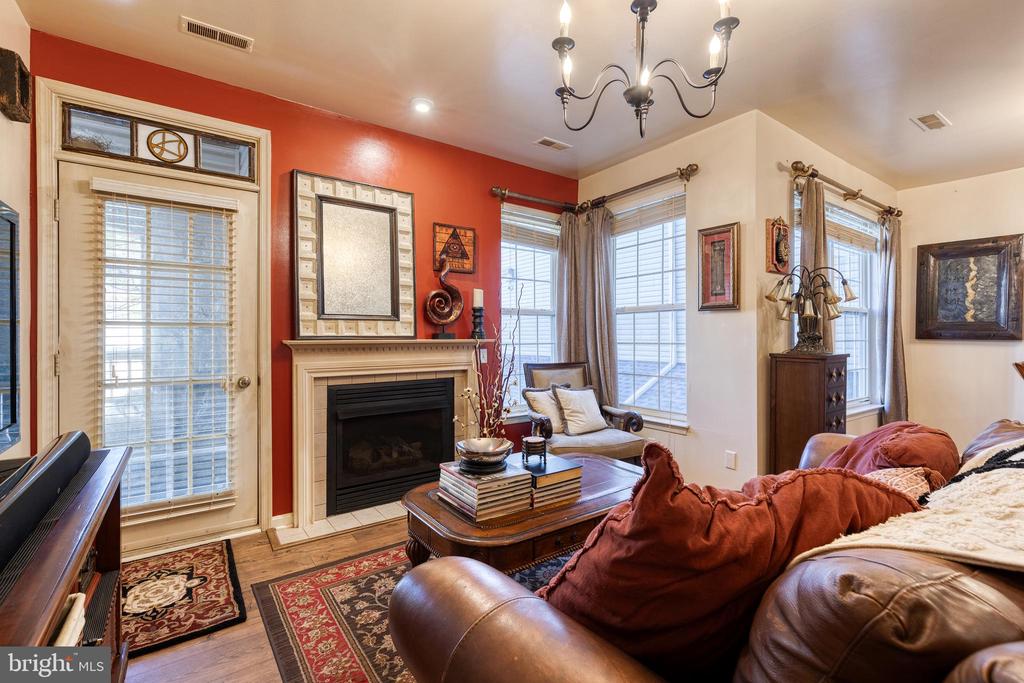 Living room with a fireplace, red accent wall, leather seating, and large windows.