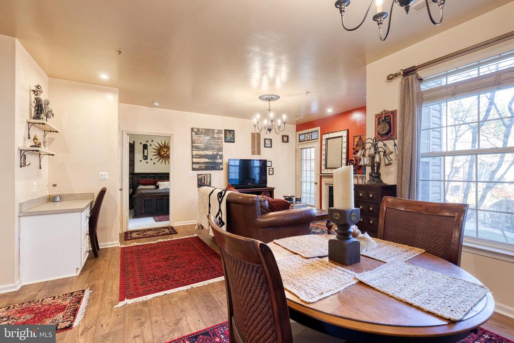 Furnished living and dining area with a round wooden table, leather seating, and large windows.