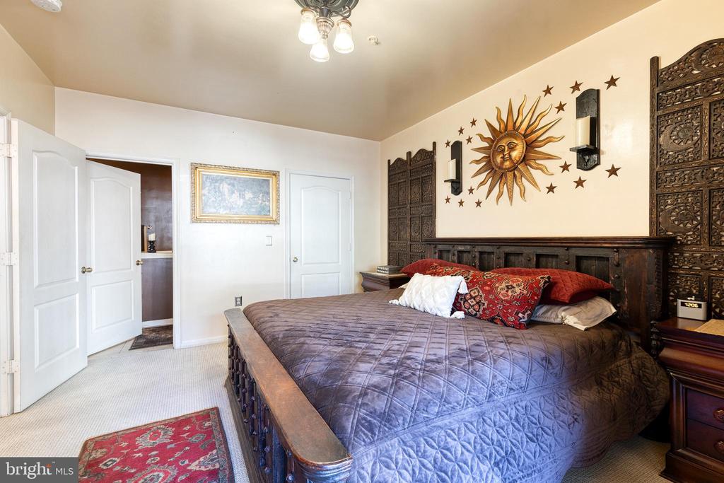 Bedroom with a carved dark-wood bed, blue quilt, and sun-and-stars wall decoration.
