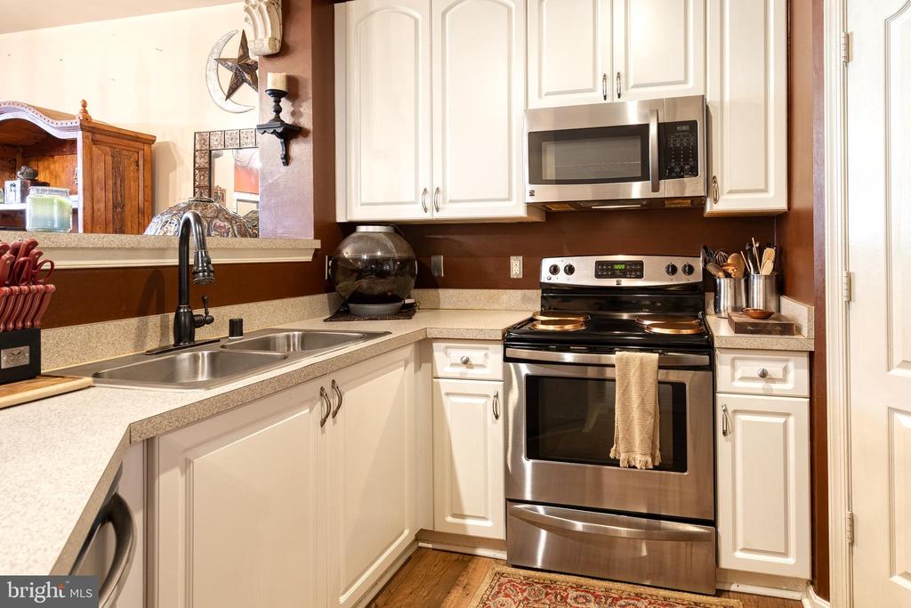 Kitchen with white cabinets, stainless steel appliances, double-basin sink, and dark brown backsplash.