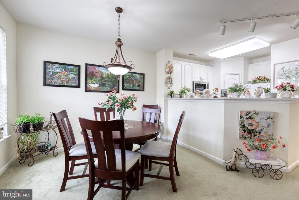 Dining room with a round wood table and chandelier beside an open kitchen.