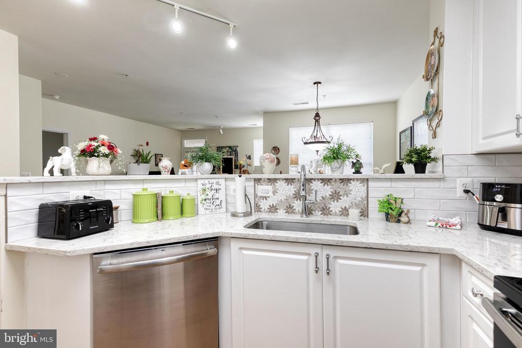 Bright white kitchen with marble-look counters, subway tile, and a stainless-steel dishwasher.