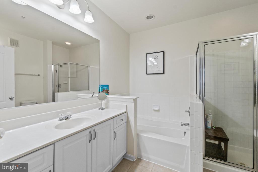 Bathroom with a long white vanity, bathtub, and glass-enclosed tiled shower.