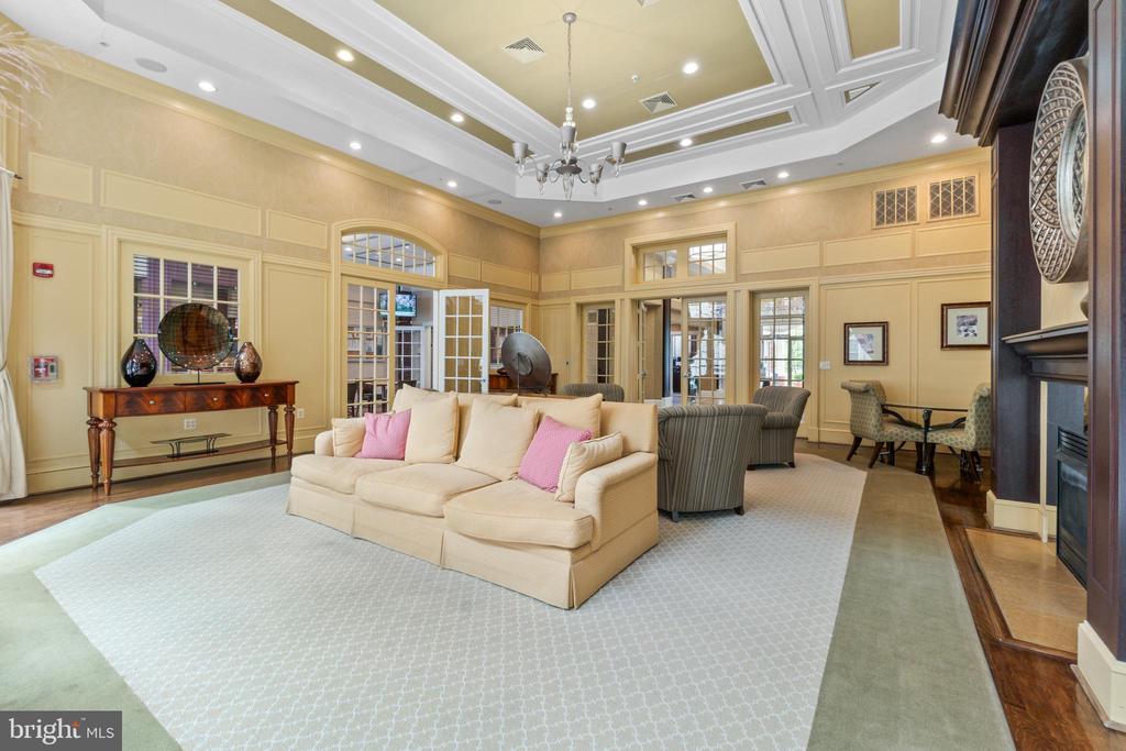 Furnished living room with cream sofas, pink accent pillows, a coffered ceiling, and a fireplace.