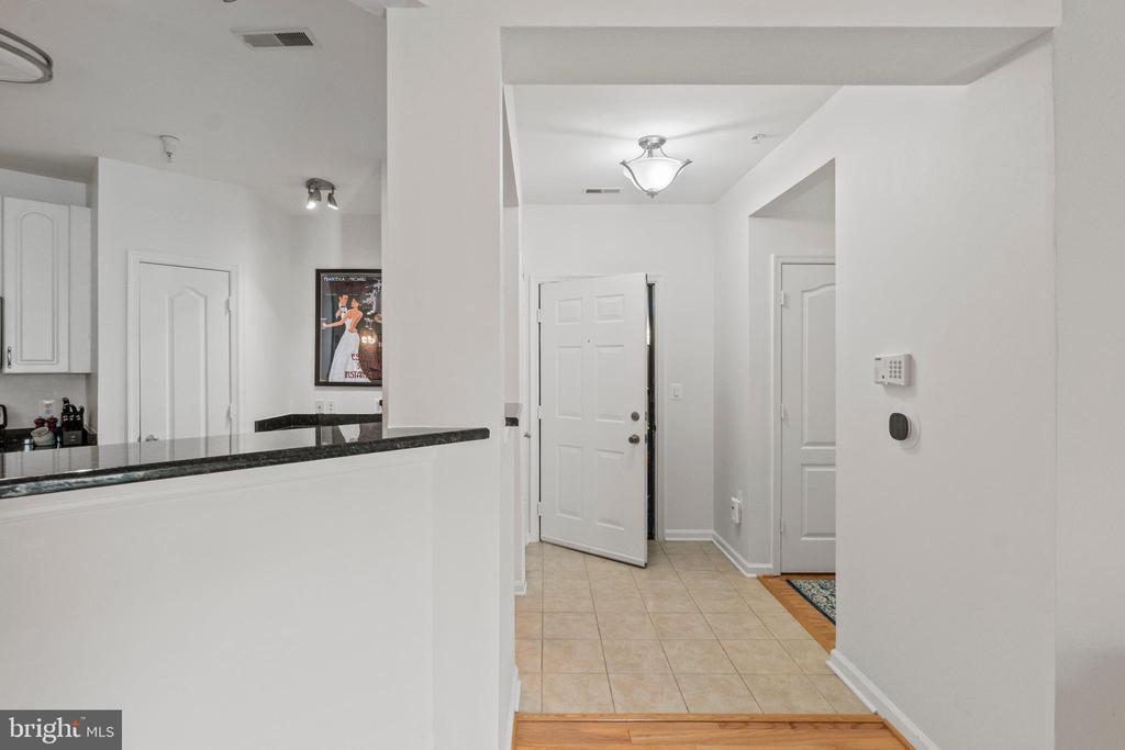 Entryway with a tiled foyer, open front door, and dark stone kitchen counter.