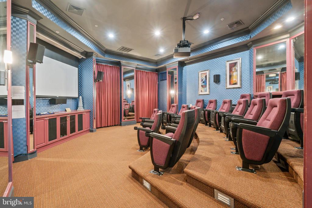 Home theater with tiered burgundy seats, a projection screen, and blue patterned walls.