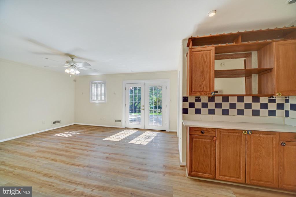 Vacant open living area with wood flooring, French doors, and oak kitchen cabinetry.