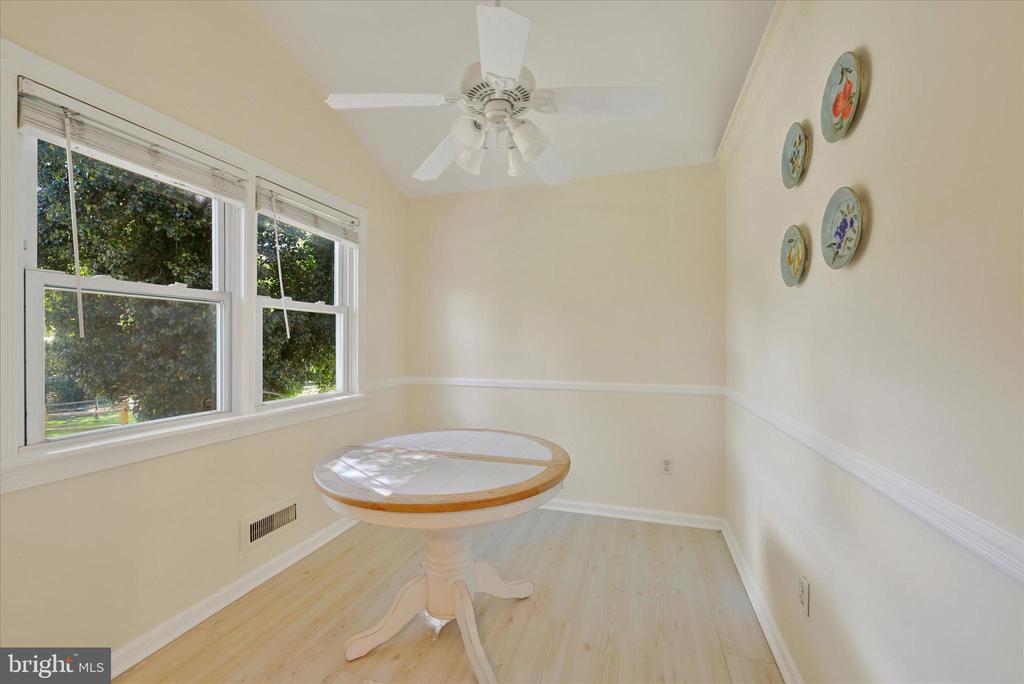 Dining nook with a round pedestal table, two large windows, and a white ceiling fan.