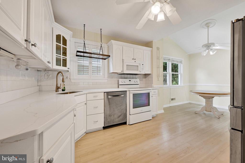 Kitchen with white cabinetry, stainless steel appliances, light wood floors, and a round dining table.