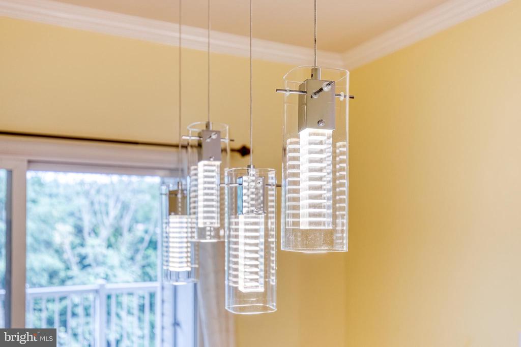 Clear glass pendant lights hang near a sliding glass door overlooking greenery.