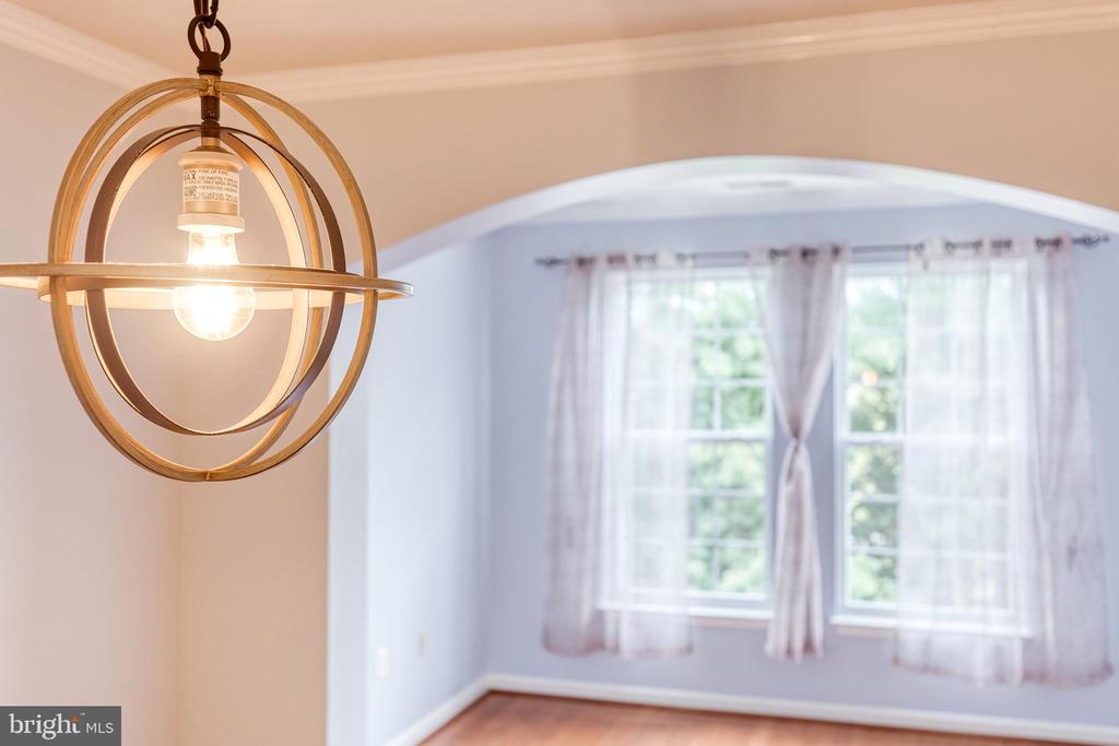 Interior room with a brass globe pendant and arched opening to a bright windowed space.