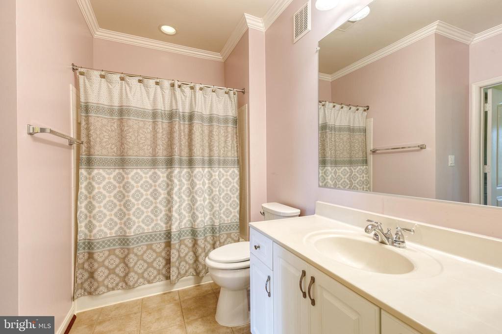 Bathroom with a patterned shower curtain and long white vanity beneath a large mirror.