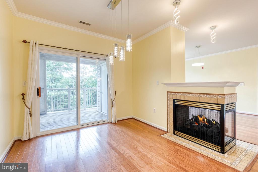 Unfurnished living area with a tiled fireplace and sliding doors to a tree-lined balcony.